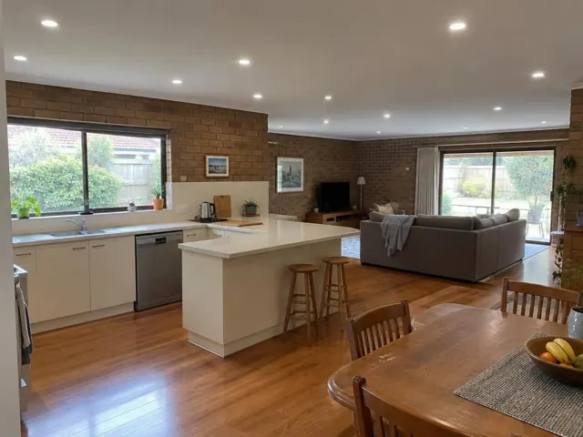 Open-plan kitchen and living room with recessed downlights in a brick home interior in Frenchs Forest