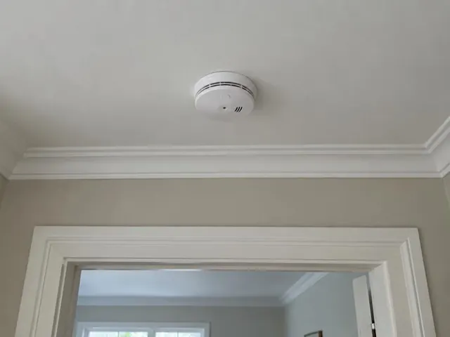 Ceiling-mounted smoke alarm in a painted hallway with decorative cornice in Roseville